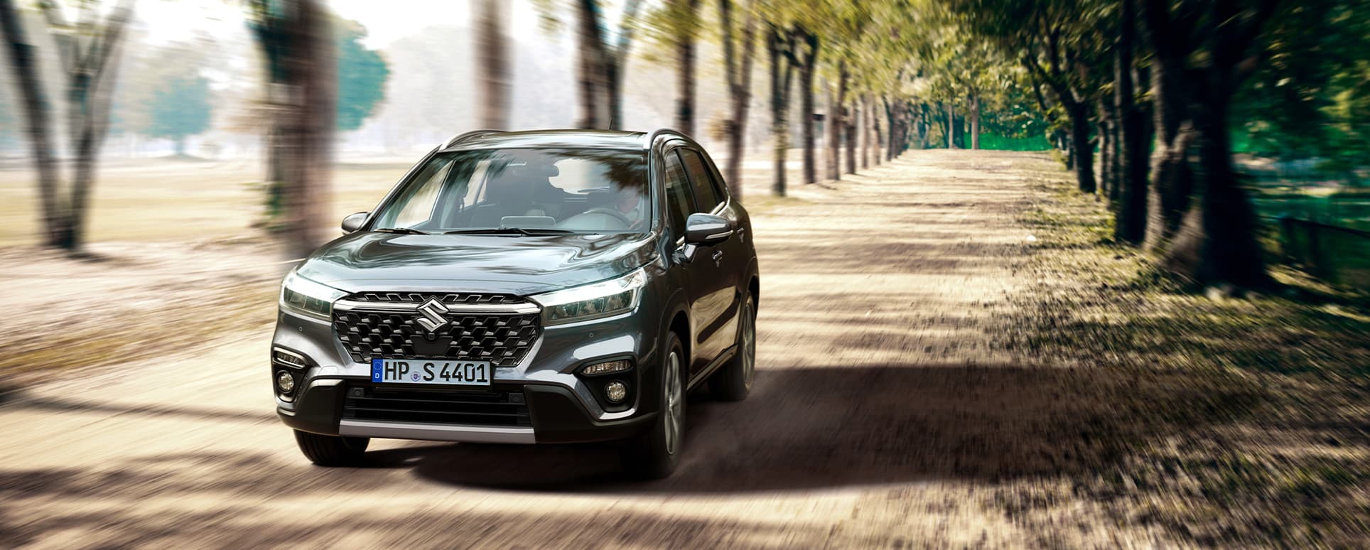 S-Cross fährt dynamisch durch eine Straße in einem Wald